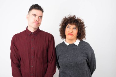  Gündelik giysiler giyen çift dudaklarıyla yukarıya bakıyor, önemli bir şey düşünerek üzülüyor, ellerini aşağıda tutuyor..