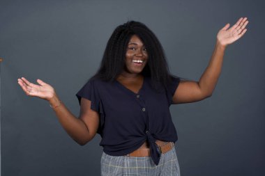 Neşeli Afrikalı Amerikalı kadın hoş bir jest yapıyor. Arka planda izole bir şekilde kollarını kaldırıyor..