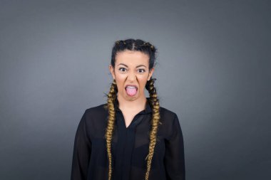 Vücut dili. Gri duvara karşı poz veren, suratını asan, bir şeyden tiksindiğini gösteren, stresli, güzel bir kız..