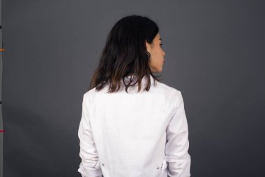 Gri duvarın karşısında duran bir doktorun arka tarafı. Stüdyo Çekimi.