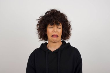 Negatif insan ifadeleri ve tavırları. Kapüşonlu bir kadının suratında iğrenç bir ifade var. Hoş olmayan bir ifade, somurtkan bir yüz, beyaz arka planda soyutlanmış bir ifade. Güvensizlik ve nefret