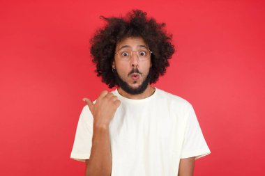 Kızıl duvara karşı afro saçlı, kafası karışmış genç bir adam. 