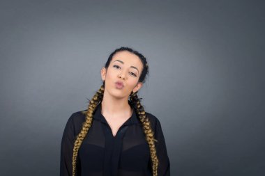 Çekici, açık renk saçlı, yuvarlak dudaklı kadın, günlük kıyafetler giyiyor, doğrudan kameraya bakıyor, memnuniyetini ifade ediyor, gri arka planda izole edilmiş..