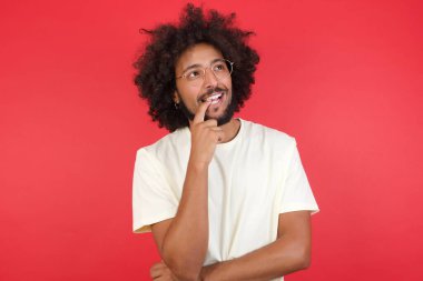 Kızıl duvara karşı düşünen afro saçlı genç bir adam. 