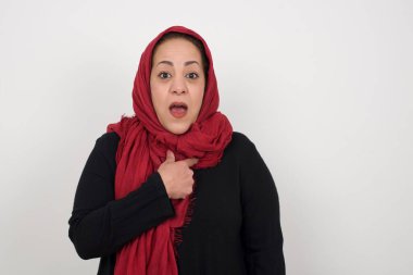 Şaşırtıcı bir şekilde olgun Müslüman bir kadın sersemlemiş durumda, şaşkın bir şekilde kendini parmağıyla göstererek, 