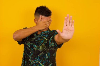 İnsanlar, vücut dili. Genç İspanyol adam avuçla gözlerini kapatıyor ve herkesten saklanmaya çalışıyor. Bana bakma, görmek istemiyorum, utanıyorum ya da korkuyorum..