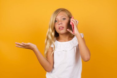 Sarı arka planda akıllı telefondan konuşan tatlı kız. 