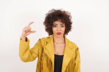  Kadın izole edilmiş arka planda, küçük boy ve ölçü sembolü gösteren el hareketleriyle. Kameraya bakıp gülümsüyor. Ölçüm konsepti.