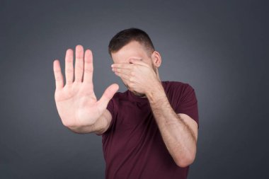 İnsanlar, vücut dili. Genç Avrupalı adam avuçla gözlerini kapar ve dur hareketi yapar. Herkesten saklanmaya çalışır. Bana bakma, görmek istemiyorum, utanıyorum ya da korkuyorum..