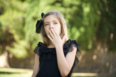 Annesi kızını çok erken uyandırdı. Uykulu, çekici, siyah elbiseli, yorgun, uykusuz, esneyen, palmiye ile ağzını kapatan bir kız.