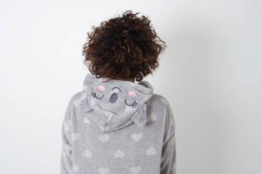 Gri duvara karşı duran pijamalı bir kızın arka görüntüsü. Stüdyo Çekimi.