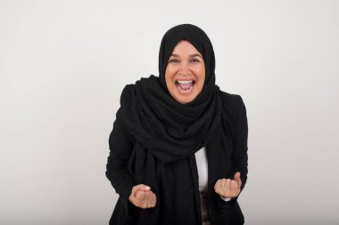 Orta yaşlı tesettürlü Müslüman kadının yakın portresi. Dalgalı saç stili. Arka planda izole edilmiş yumruklar..