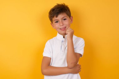 Sarı duvara gülümseyen sevimli çocuk.  