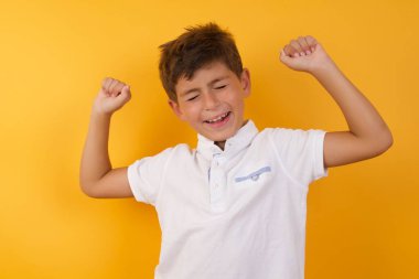 Yakışıklı çocuk sarı duvarda mutlu.  