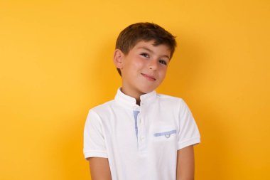 Sarı duvara gülümseyen sevimli çocuk.  