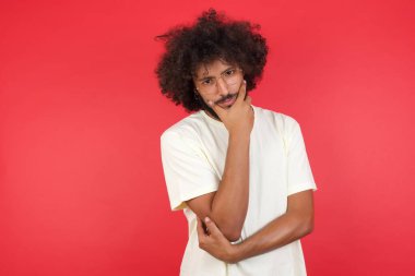 Kızıl duvara karşı düşünen afro saçlı genç bir adam.   