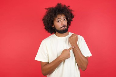 Kızıl duvara el uzatan afro saçlı genç bir adam.   