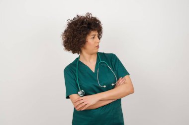 İçeride kollarını kavuşturmuş, tıbbi üniforma giyen üzgün bir Arap doktorun görüntüsü. Kötü haberleri dinledikten sonra hayal kırıklığına uğramış bir ifadeyle bakıyorum. Kendine güvenen kız..