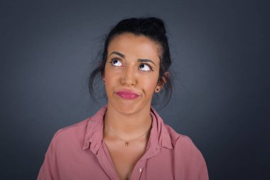 Hüzünlü, merak eden genç bir kadın dudaklarının arasından bakarak, önemli bir şeyi düşünerek üzülüyor. 