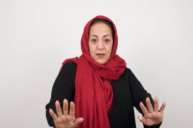 Güzel esmer kadın, izole edilmiş arka planda korkmuş ve korkudan dehşete düşmüş, ve tiksindirici ifade iki elinle hareket etmeyi kes, orada kal. Panik konsepti. Stüdyoda poz veren başörtüsü takan orta yaşlı bir Arap kadın.