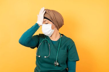Yüzünde maske olan, hayal kırıklığına uğramış Arap kadın doktor baş ağrısı yüzünden depresyona girdi. Suratı asık, kafası karışmış, stresli görünen, acı çeken bir kadın.