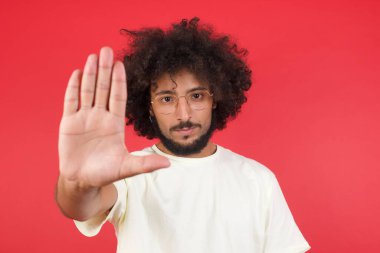 Kızıl duvarda duran afro saçlı genç adam. 