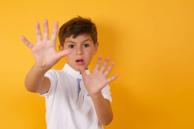 Sarı duvarda duran sevimli çocuk.  