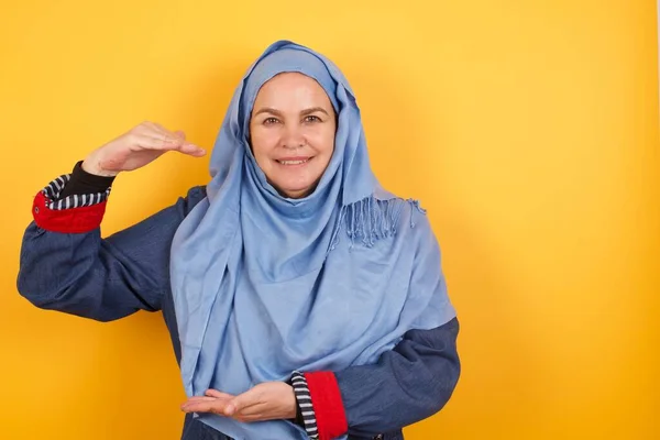 Muzułmanka Średnim Wieku Hidżabie Nad Odosobnionym Tle Gestykulując Dłońmi Pokazującymi — Zdjęcie stockowe