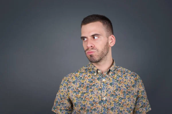 Hoş görünümlü genç bir erkek öğrenci, düşünceli bir şekilde kenara bakıyor, üniversiteden sonra eylemler planlıyor, ne yapacağını hayal ediyor. Zeki adam yeni projesini düşünüyor. Boşluğu griye kopyala.