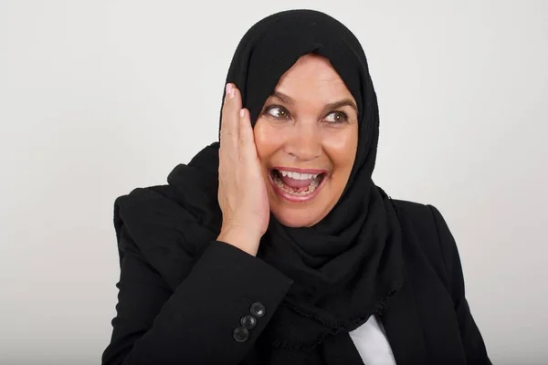 黒いヒジャーブのイスラム教徒の女性は 顔に手を見ながら興奮しました 興奮する側面を見ている幸せな若い女性 灰色の背景にある白人女性モデル — ストック写真