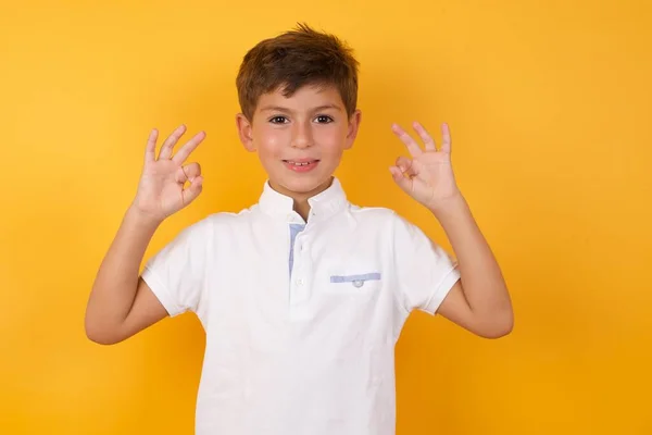 Schattig Jongen Tonen Tegen Gele Muur — Stockfoto