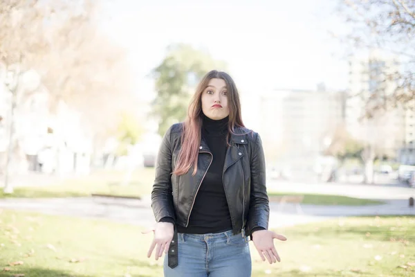 young beautiful woman is confused   in the park