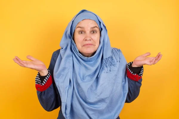 头晕目眩 毫无头绪的中年穆斯林妇女 手臂伸出 耸了耸肩 谁在乎 那又怎样 我不知道 — 图库照片