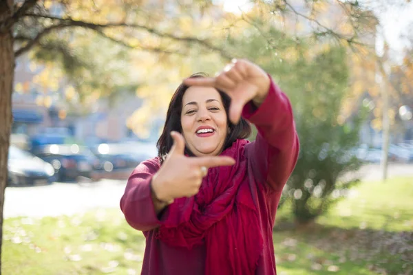 Güzel orta yaşlı Arap kadın parkta çerçeve yapıyor.  