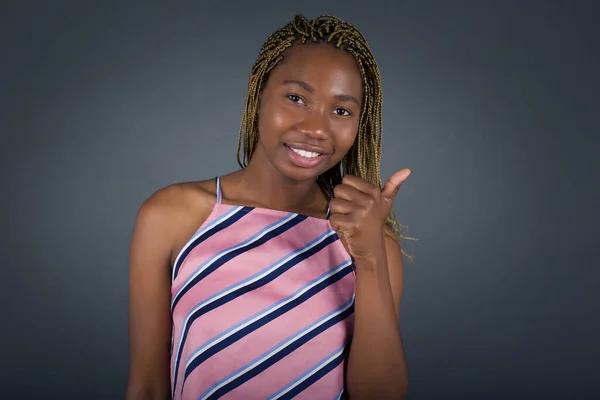 灰色の背景に立って親指を放つ幸せな笑顔のアフリカ系アメリカ人女性の肖像画 — ストック写真