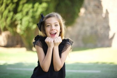 Stüdyo çekimlerinde, siyah elbiseli güzel kız ellerini çenesinin altında tutuyor, keyifli bir ruh hali içinde, ertesi gün için arkadaşlarının fikrini seviyor.