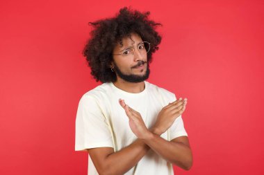 Kızıl duvara karşı hayır işareti yapan afro saçlı genç adam.   