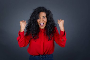 Güçlü, kararlı, kollarını kaldıran, yumruklarını sıkan, neşe ve heyecanla haykıran genç bir kadının belini kaldırın..