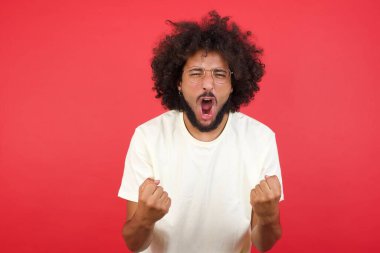 Kızıl duvarda yumrukları olan afro saçlı genç bir adam.   