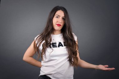 Güzel bir kadın Gri arka planda duruyor ve avuç içini gösteriyor. 