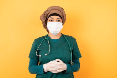 Yeşil üniformalı, kendine güvenen yüzüyle el ele tutuşan güzel, Müslüman doktor kadın..