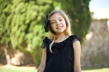 Geniş gülüşlü güzel bir kız, parkta beyaz dişlerini gösteriyor. 