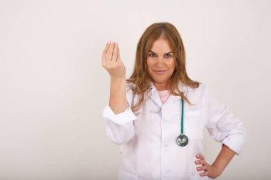 What the hell are you talking about. Shot of frustrated  mature caucasian doctor woman wearing medical uniform gesturing with raised hand doing Italian gesture, frowning, being displeased and confused with dumb question.