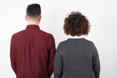 Beyaz duvarın önünde duran kadın ve erkeğin arka görüntüsü. Stüdyo Çekimi.