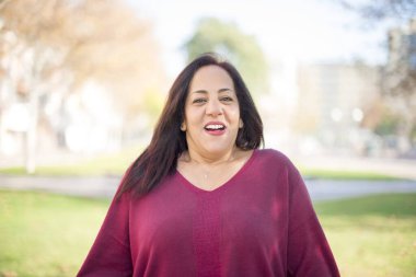 Parkta gülümseyen orta yaşlı güzel bir Arap kadın.  