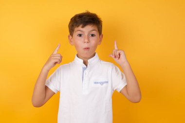 Sarı duvara işaret eden sevimli çocuk.  
