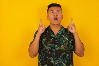 Yakışıklı İspanyol bir adamın portresi izole edilmiş arka planda şaşkın şaşkın bakıyor ve parmaklarıyla garip bir şey gösteriyor..