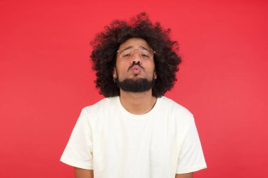 Kızıl duvarda öpüşme gösteren afro saçlı genç adam. 