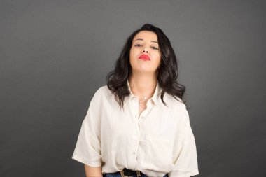 Güzel esmer kadın poz veriyor. Gri arkaplanda duruyor. 