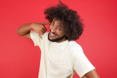 Afro saçlı genç adam bana kırmızı duvara karşı jest yap de. 